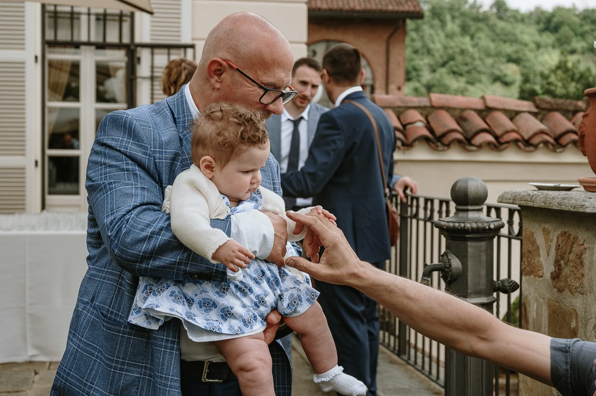 Fotografo matrimonio Torino. Momento aperitivo a Villa Ala. Invitato con una bambina in braccio.