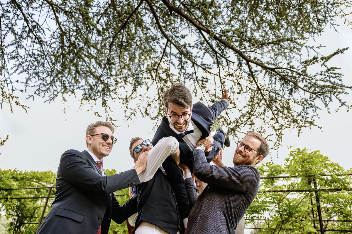 Fotografo matrimonio Torino. Momento aperitivo a Villa Ala. Amici prendono in braccio lo sposo.