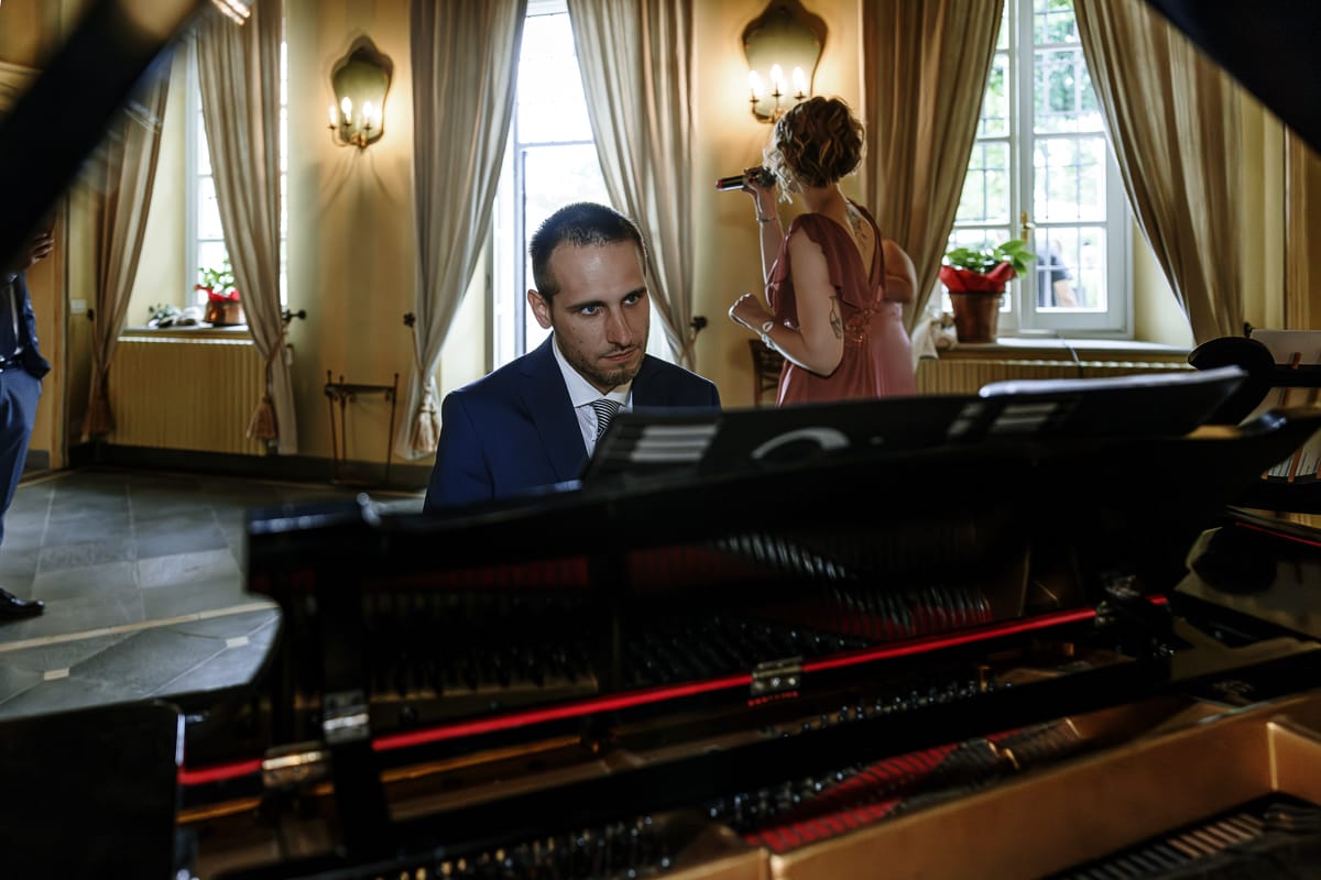 Fotografo matrimonio Torino. Momento aperitivo a Villa Ala. Testimone dello sposo suona il piano e la fidanzata canta.