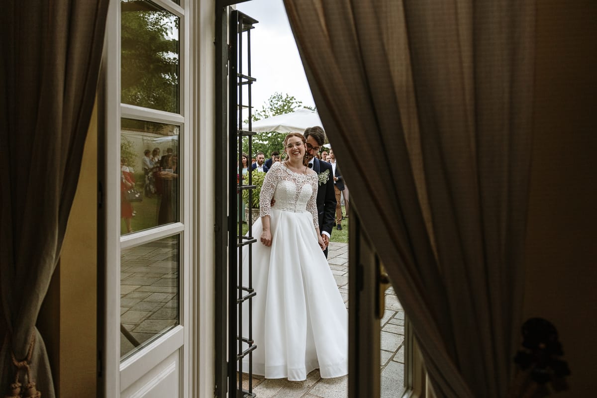 Fotografo matrimonio Torino. Momento aperitivo a Villa Ala. Sposi ascoltano gli amici che suonano il pianoforte e cantano.