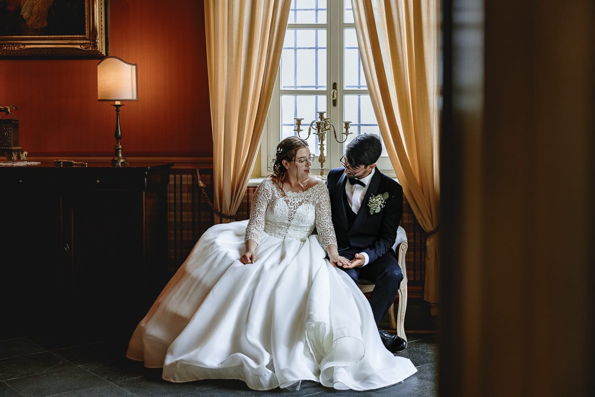 Fotografo matrimonio Torino. Ritratto degli sposi seduti su di un divano in una bella sala di Villa Ala.