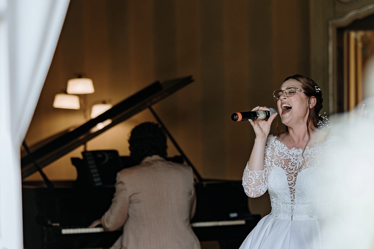 Fotografo matrimonio Torino. La sposa canta nel salone di Villa Ala e una maestro suona il pianoforte a coda.