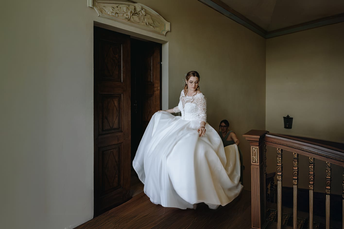Fotografo matrimonio Torino. La sposa sale al piano superiore di Villa Ala mentre la sorella le tiene la coda del vestito.