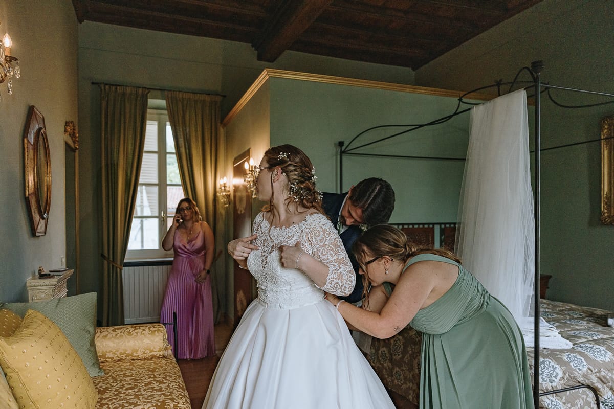 Fotografo matrimonio Torino. La sposa è in una delle bellissime stanze di Villa Ala. mentre i testimoni modificano il look dell'abito.