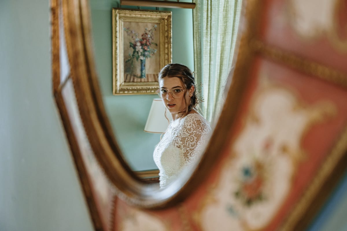 Fotografo matrimonio Torino. La sposa riflessa in un antico specchio in una delle bellissime camere di Villa Ala.