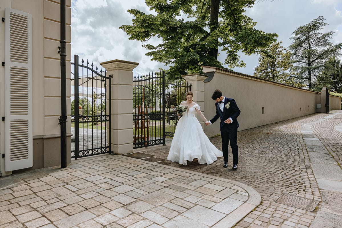 Fotografo matrimonio Torino. Gli sposi si incamminano verso la veranda vetrata di Villa Ala