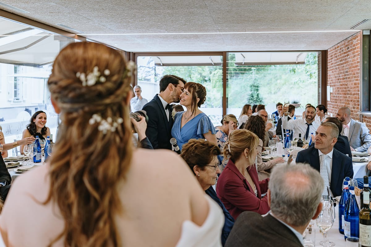 Fotografo matrimonio Torino. Pranzo nuziale a Villa Ala. Sposo bacia la mamma. sposa li guarda.