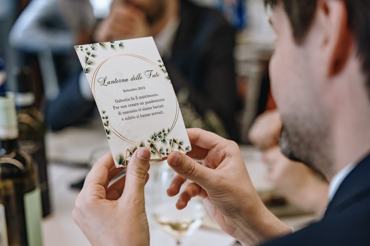 Fotografo matrimonio Torino. Pranzo nuziale a Villa Ala. Invitato legge il segnatavolo.