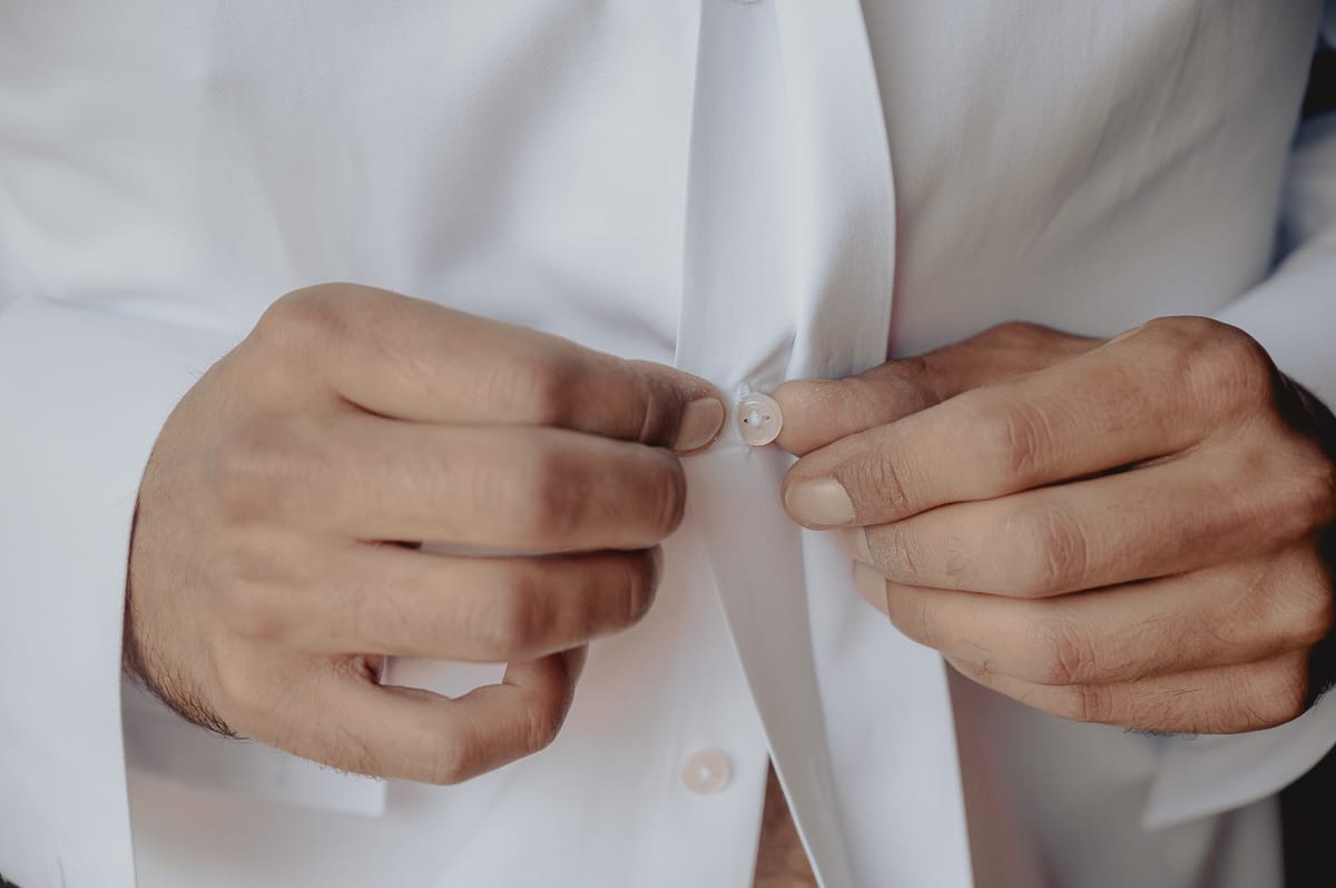 preparazione dello sposo a Chieri. Sposo si abbottona la camicia.