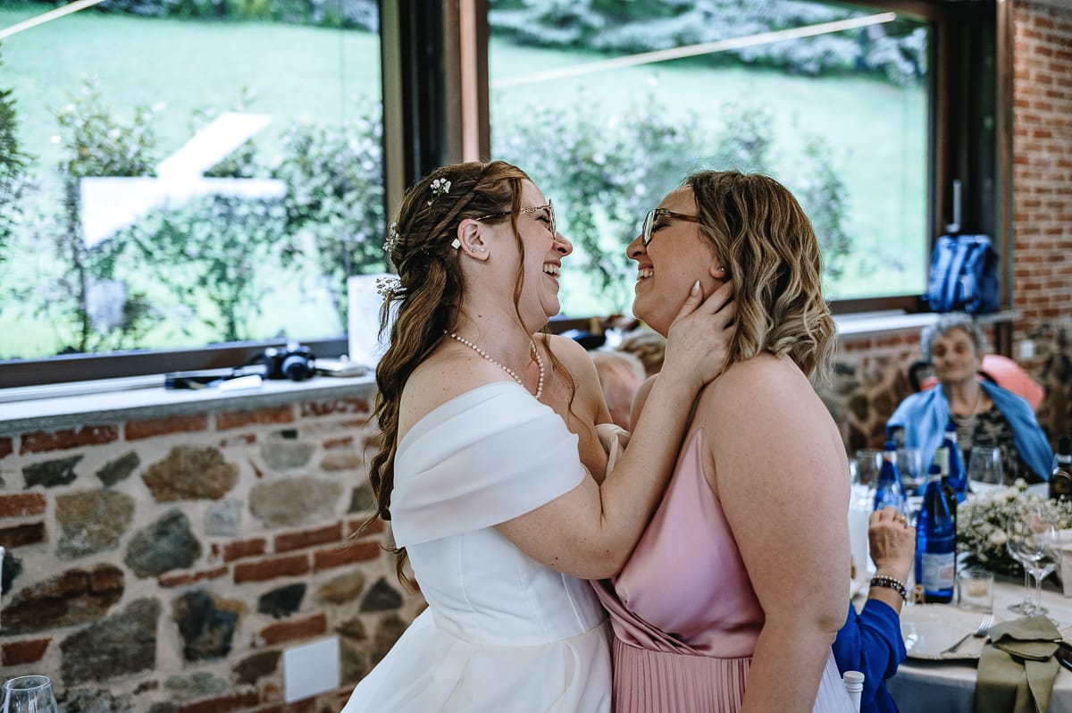 Fotografo matrimonio Torino. Pranzo nuziale a Villa Ala. Sposa e sorella si abbracciano e si guardano.