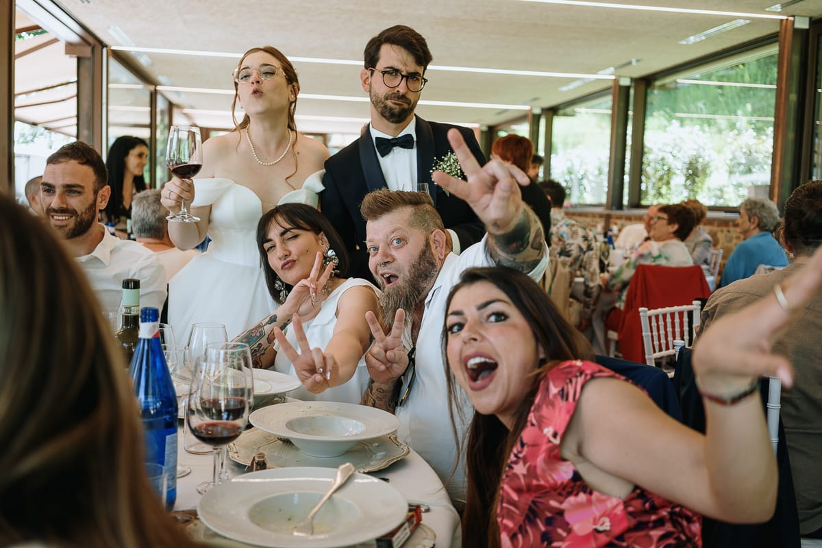 Fotografo matrimonio Torino. Pranzo nuziale a Villa Ala. Sposi brindano con alcuni amici.