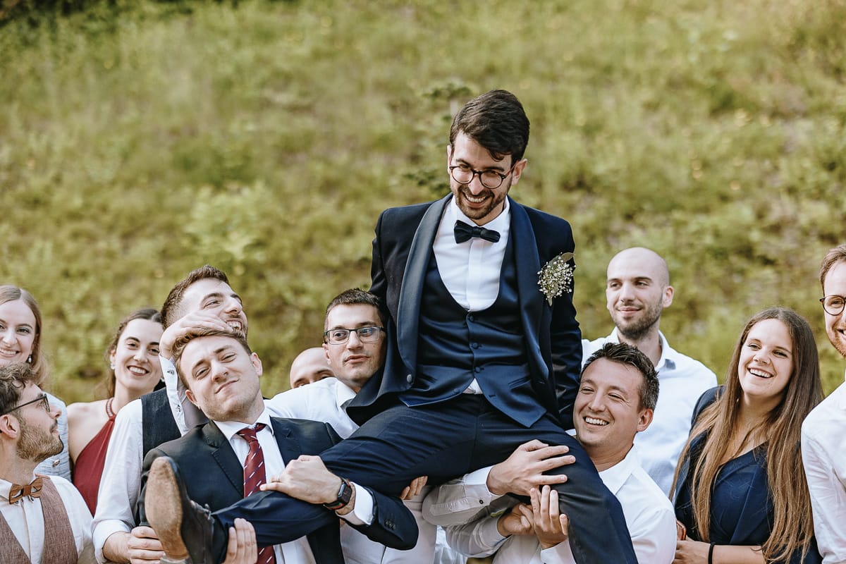 Fotografo matrimonio Torino. Amici sollevano lo sposo nel giardino di Villa Ala.