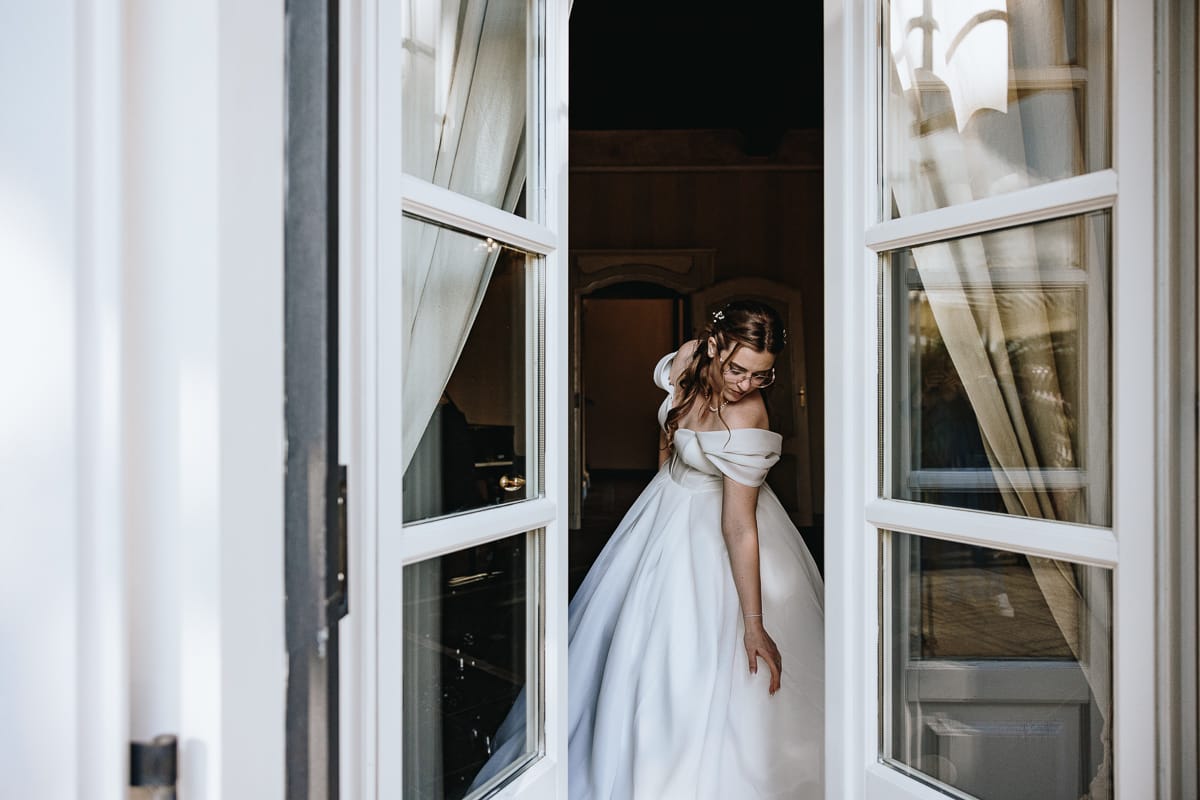 Fotografo matrimonio Torino. Sposa in una sala di Villa Ala si sistema la gonna del vestito.