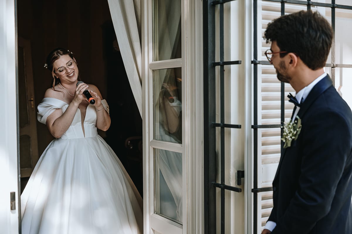 Fotografo matrimonio Torino. La sposa canta in una sala di Villa Ala mentre lo sposo la guarda.