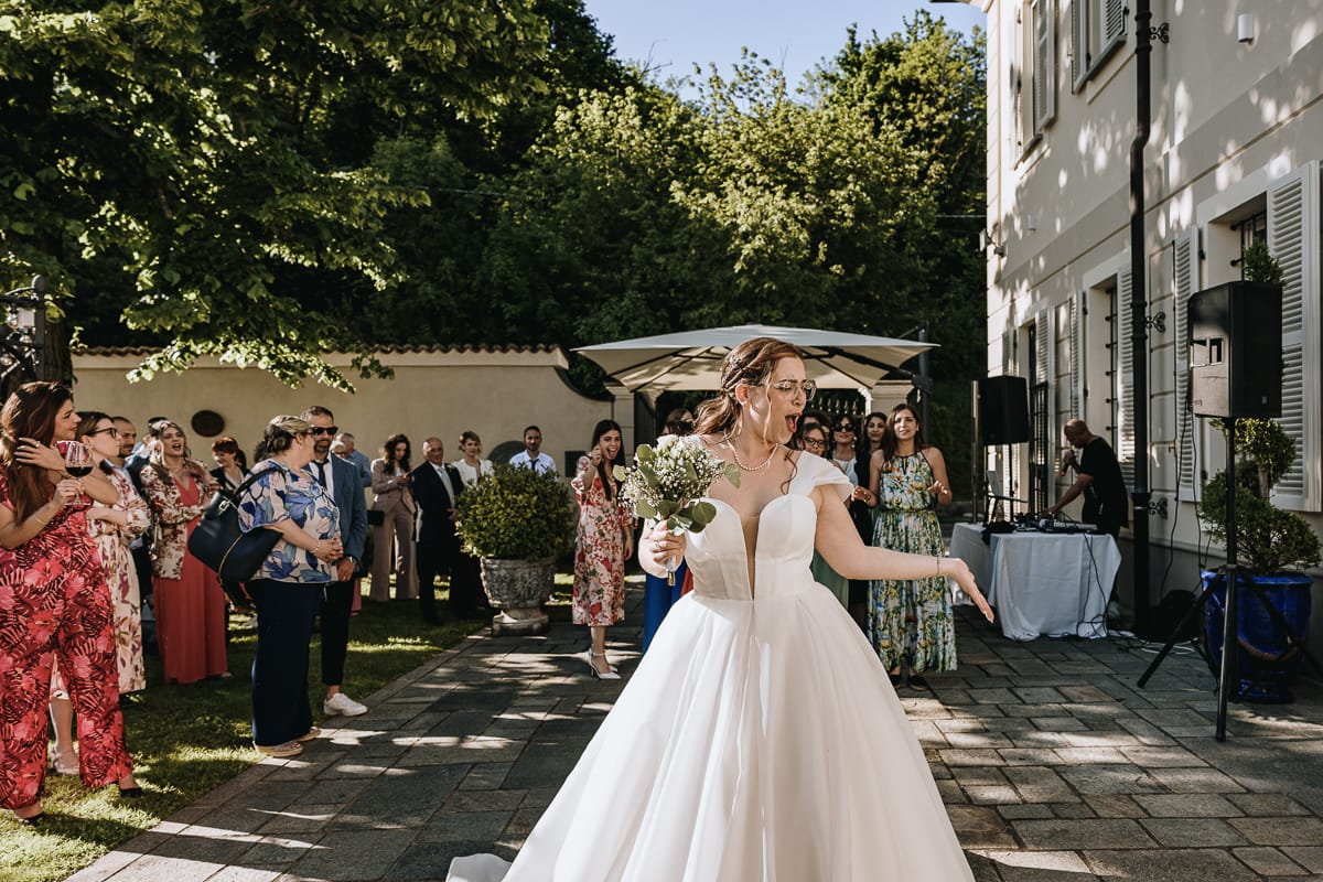 Fotografo matrimonio Torino. La sposa si prepara a lanciare il bouquet nel giardino di Villa Ala.