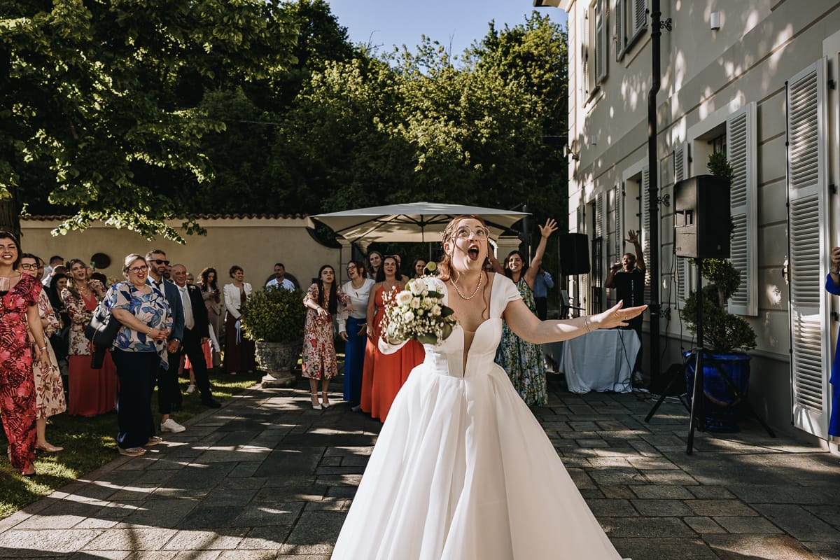 Fotografo matrimonio Torino. La sposa si prepara a lanciare il bouquet nel giardino di Villa Ala. La sposa ha un'espressione buffa.