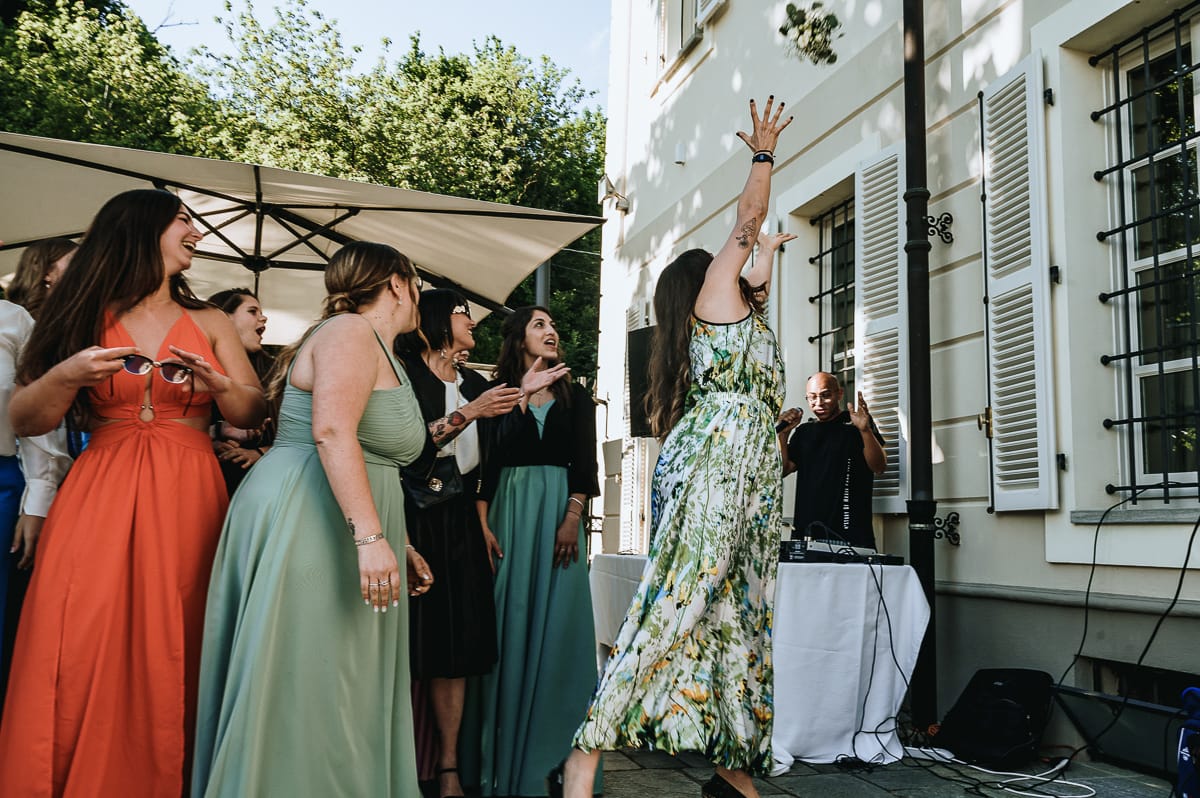 Fotografo matrimonio Torino. La sposa lancia il bouquet nel giardino di Villa Ala. Una ragazza lo prende con un'acrobazia