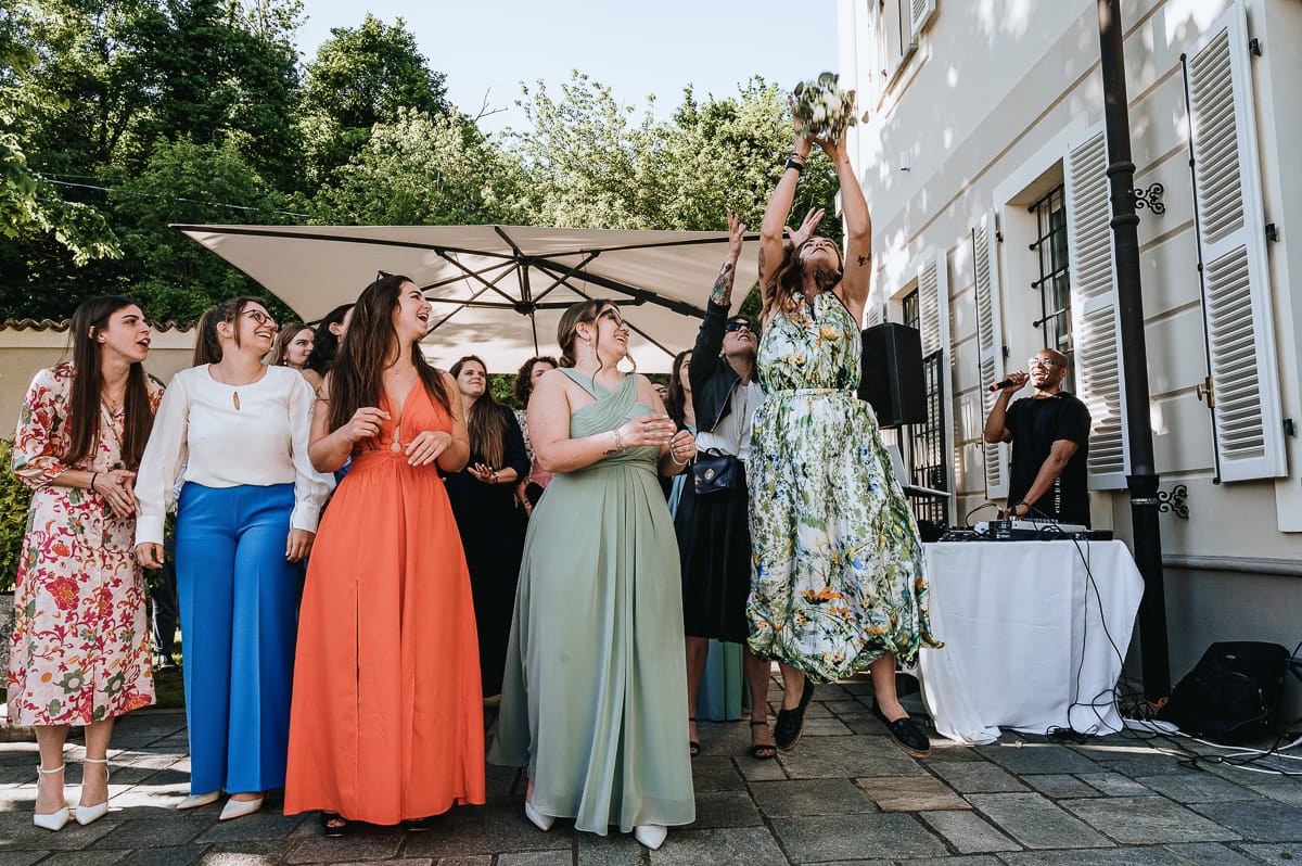 Fotografo matrimonio Torino. La sposa lancia il bouquet nel giardino di Villa Ala. Una ragazza lo prende con un'acrobazia.