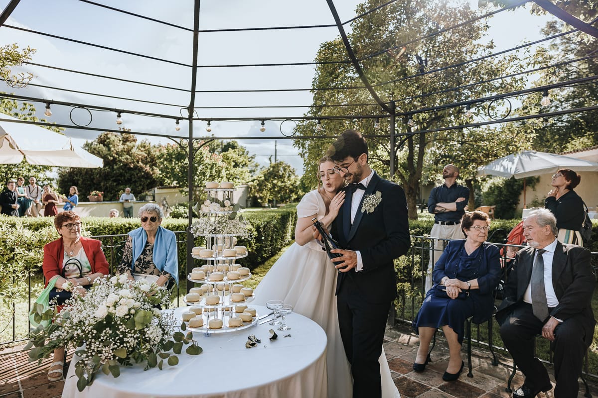 Fotografo matrimonio Torino. Taglio della torta sotto un gazebo nel giardino di Villa Ala.