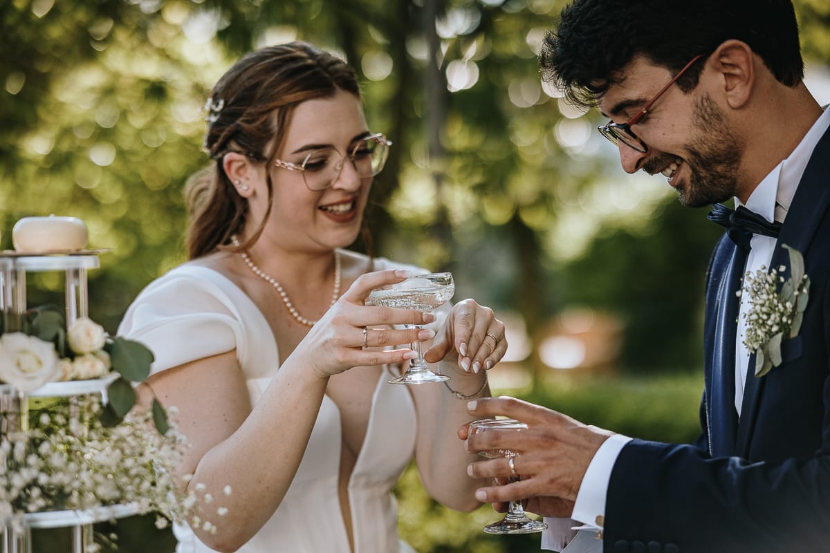 Fotografo matrimonio Torino. Taglio della torta sotto un gazebo nel giardino di Villa Ala. Gli sposi si apprestano a brindare.