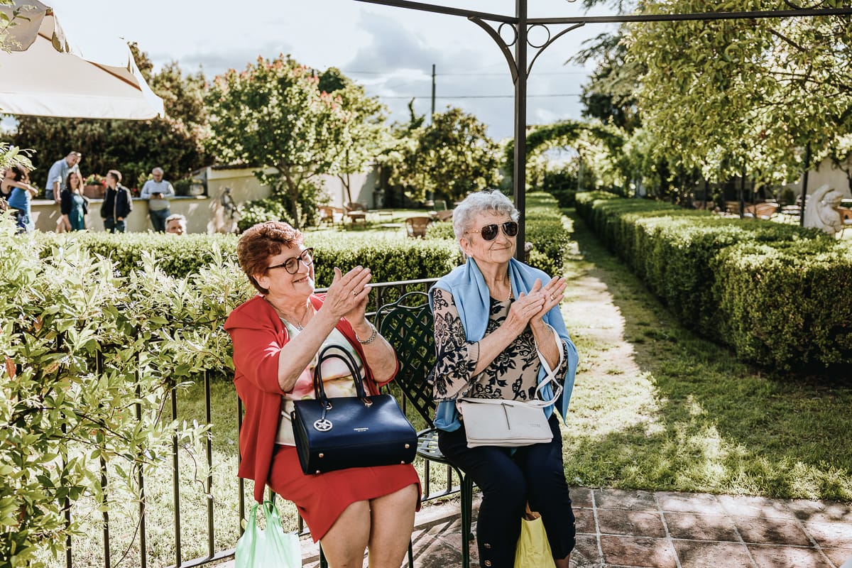 Fotografo matrimonio Torino. Taglio della torta sotto un gazebo nel giardino di Villa Ala. Invitate applaudono.