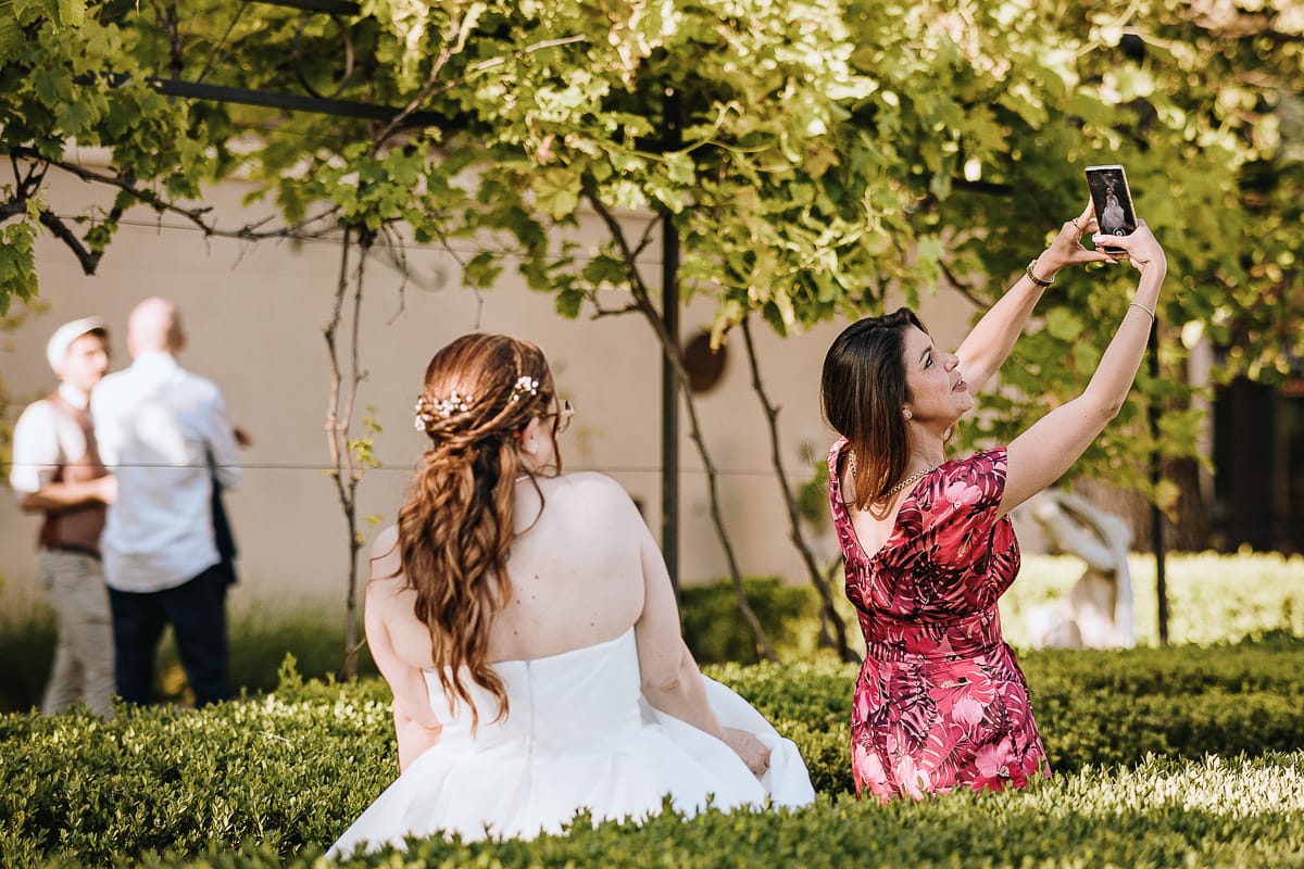 Fotografo matrimonio Torino. Sposa con un'amica che fa un selfie nel giardino all'italiana di Villa Ala.