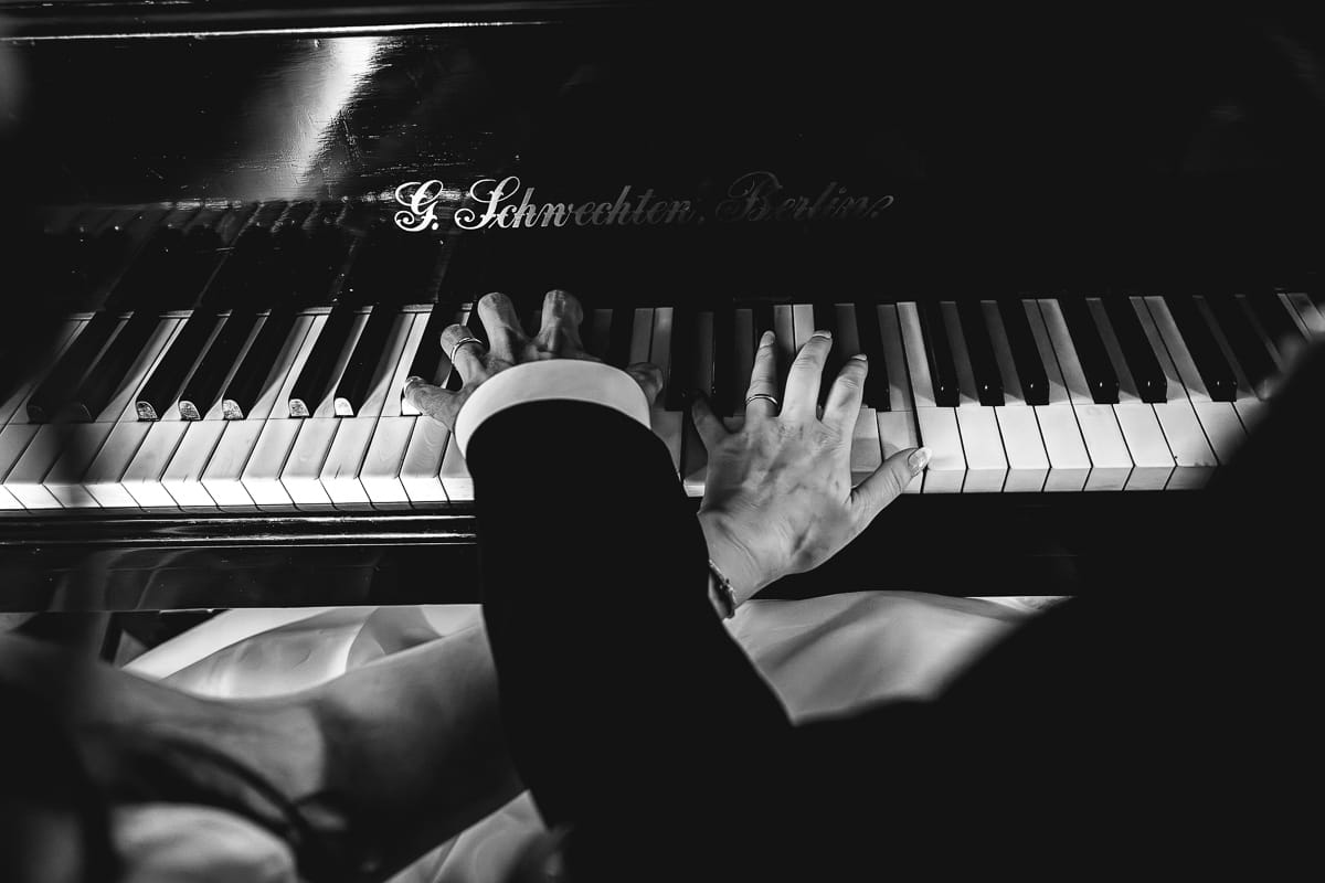 Fotografo matrimonio Torino. Gli sposi suonano il pianoforte in una sala di Villa Ala. Bianco e nero.