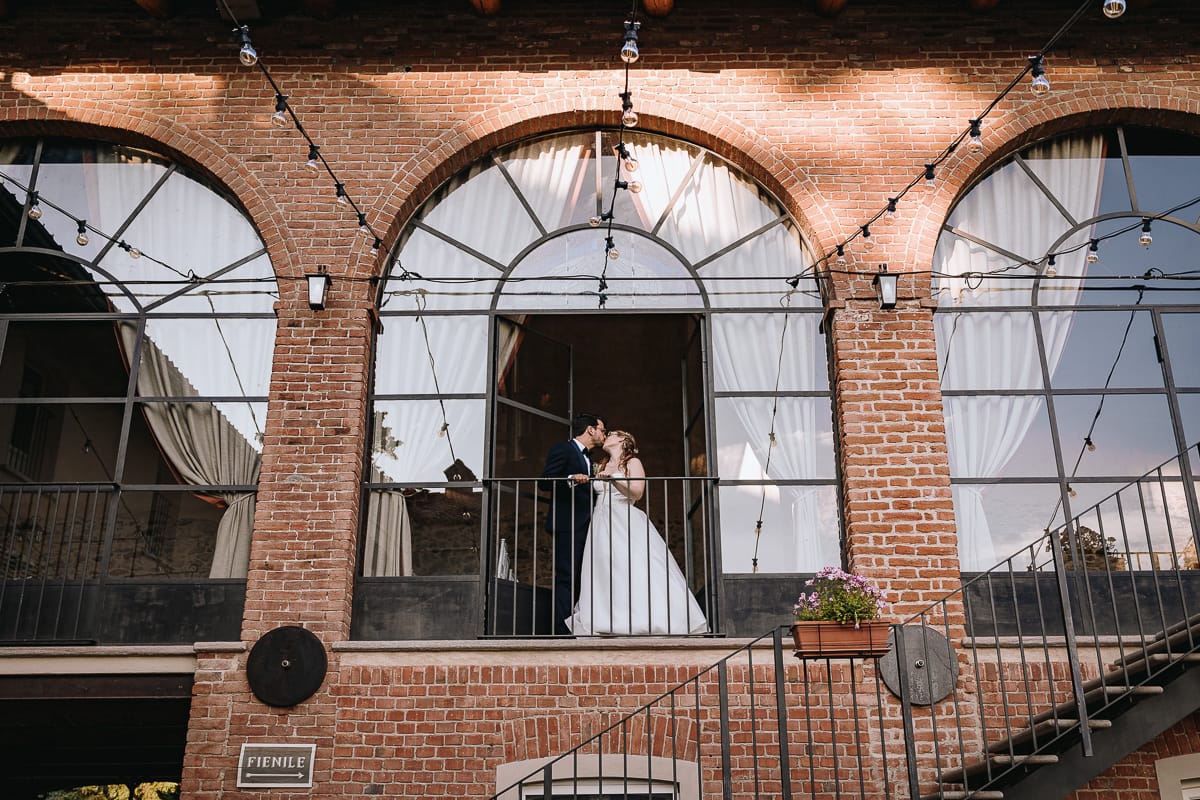 Fotografo matrimonio Torino. Sposi nell'ex fienile di Villa ala. Sposi al balcone si baciano.