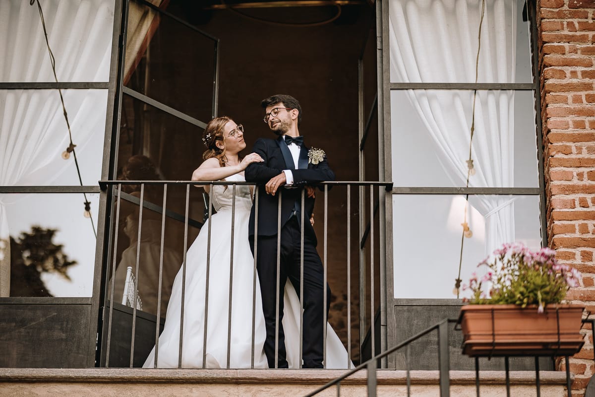 Fotografo matrimonio Torino. Sposi nell'ex fienile di Villa ala. Sposi al balcone si guardano.