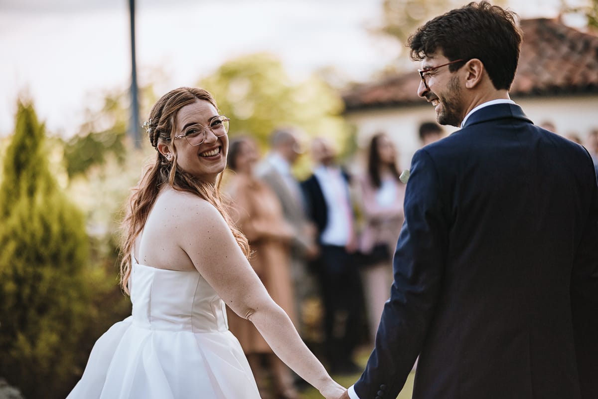 Fotografo matrimonio Torino. Sposi nella corte interna di Villa Ala. Sposi vanno verso gli invitati guardano dietro di loro.