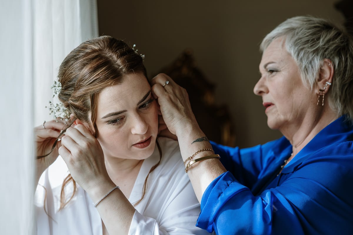 Preparazione della sposa a Madonna della Scala. mamma aiuta la sposa ad indossare gli orecchini.