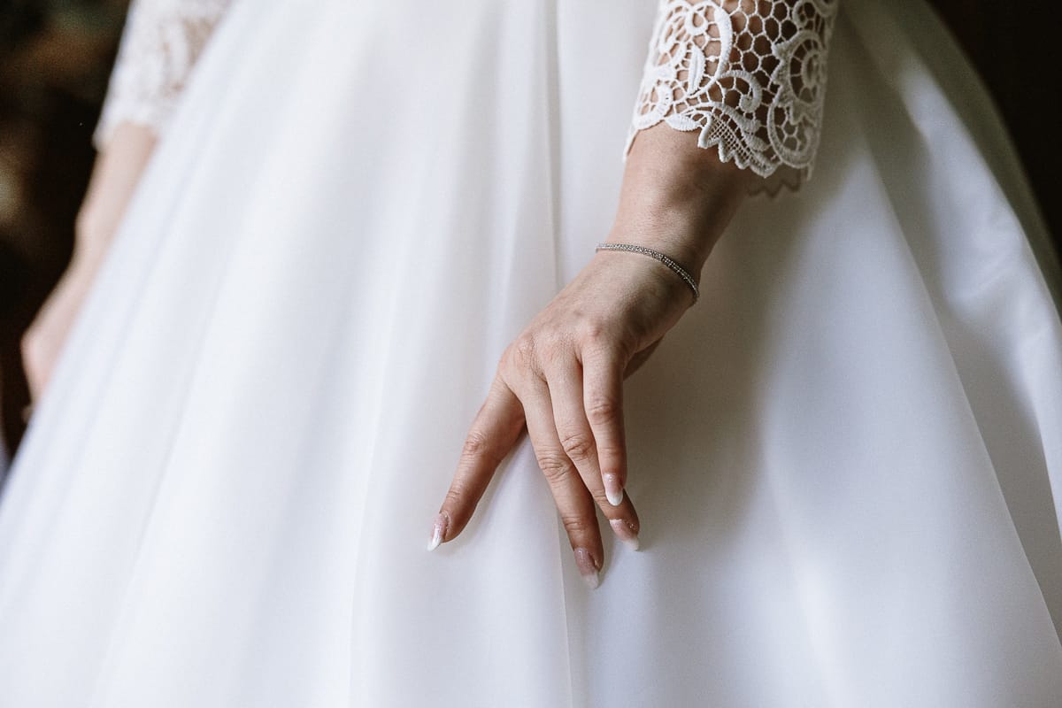 Preparazione della sposa a Madonna della Scala. Dettaglio della mano della sposa sulla gonna di tulle.