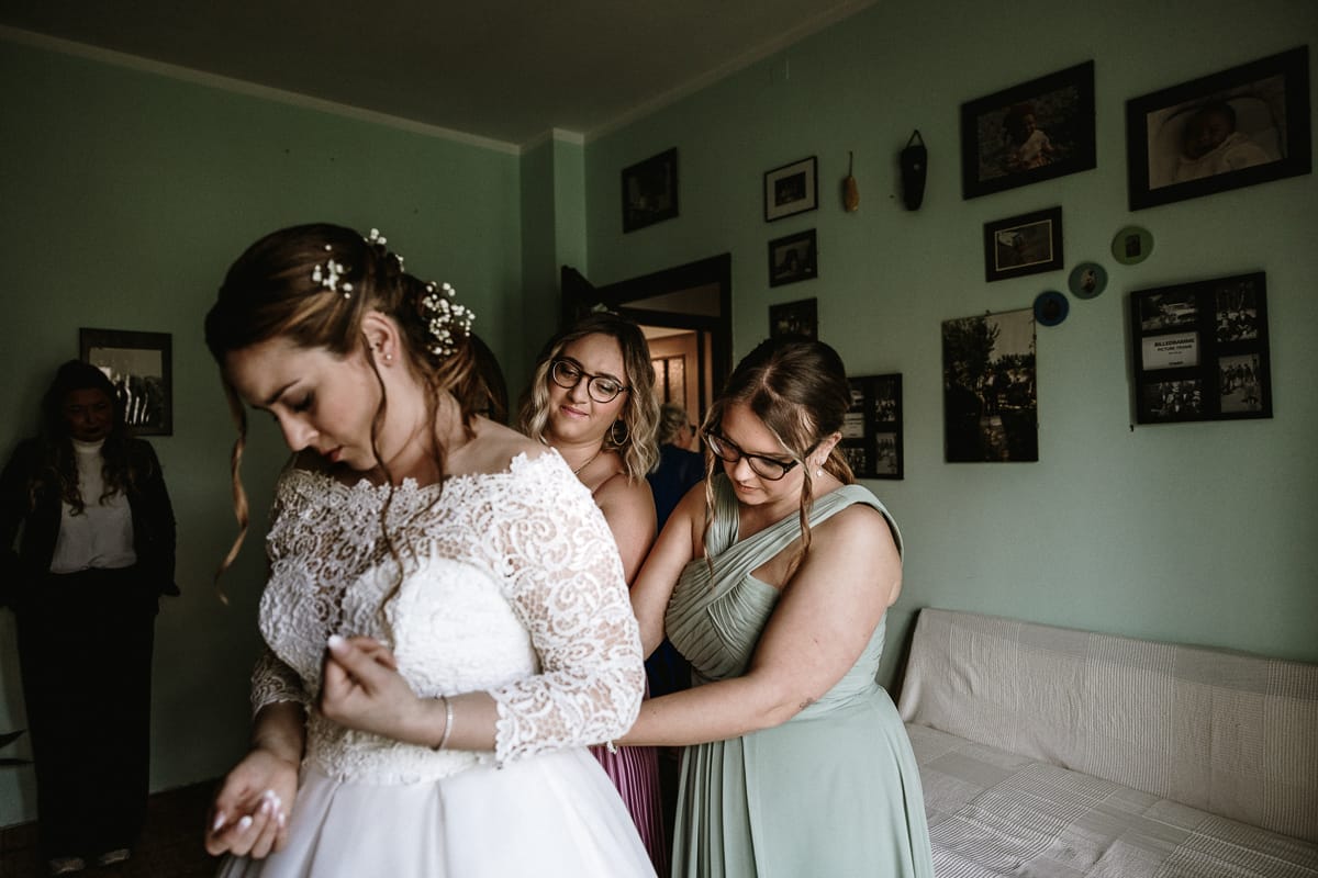 Preparazione della sposa a Madonna della Scala. Le damigelle abbottonano l'abito della sposa.