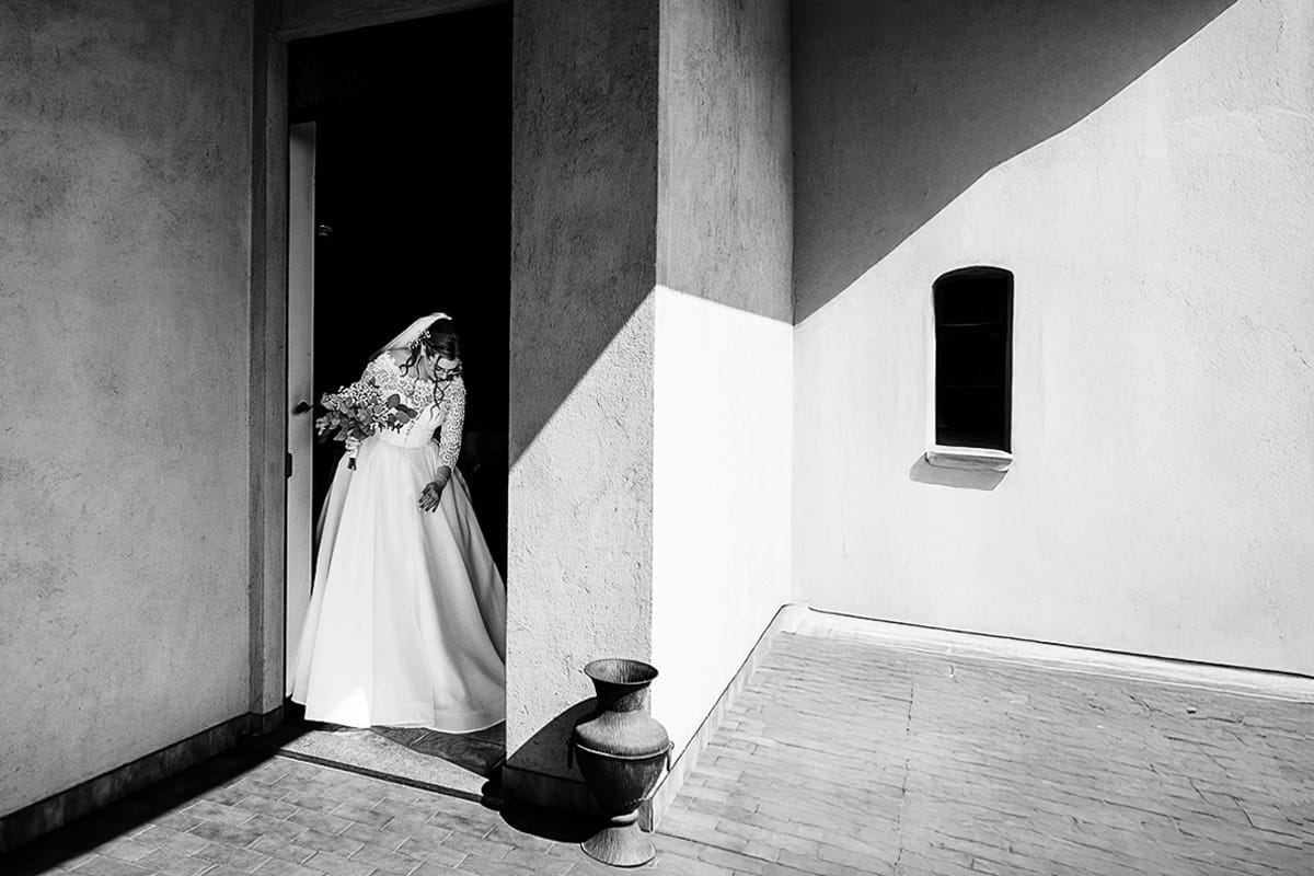 Preparazione della sposa a Madonna della Scala. Sposa esce di casa in un mattino molto soleggiato. Fotografia minimal in bianco e nero.