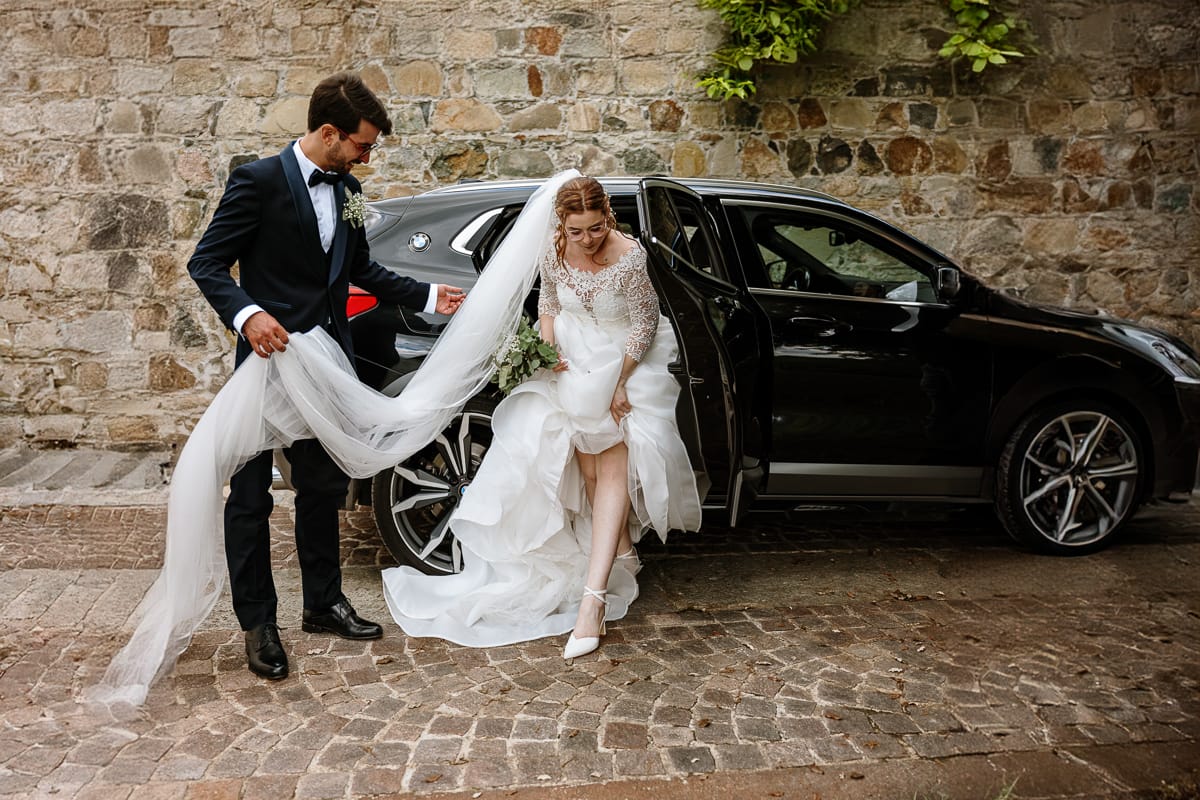 Matrimonio a Villa Ala di Rivalba (TO). Sposa scende dall'auto. Sposo l'aiuta con il velo.
