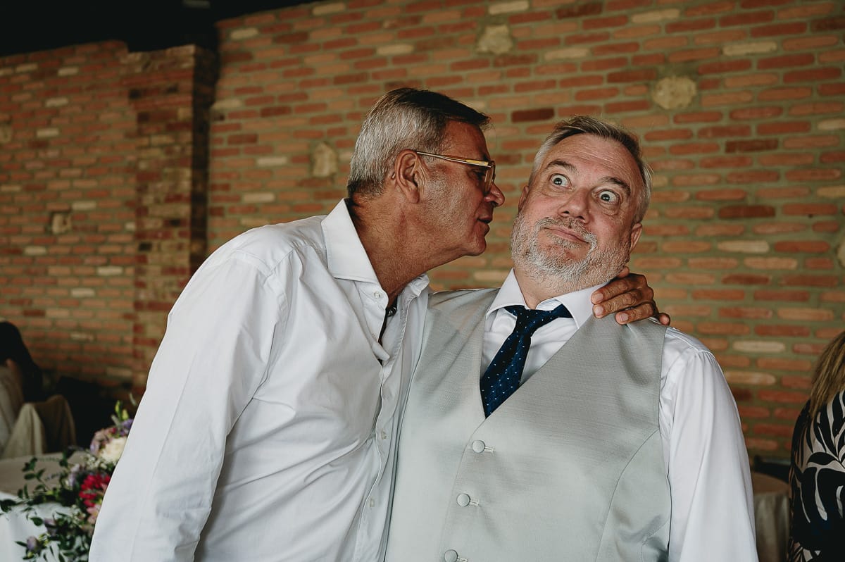 Fotografo matrimonio in Monferrato. Matrimonio di Serena e Fabrizio al Vecchio Castagno di Cocconato d'Asti. Sposo con amico che fa finta di volerlo baciare.