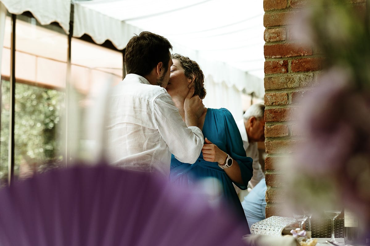 Fotografo matrimonio in Monferrato. Matrimonio di Serena e Fabrizio al Vecchio Castagno di Cocconato d'Asti. Giovane coppia di invitati che si baciano.