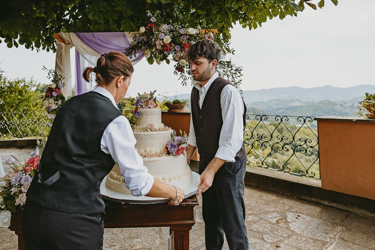 Fotografo matrimonio in Monferrato. Matrimonio di Serena e Fabrizio al Vecchio Castagno di Cocconato d'Asti. Camerieri portano la torta.