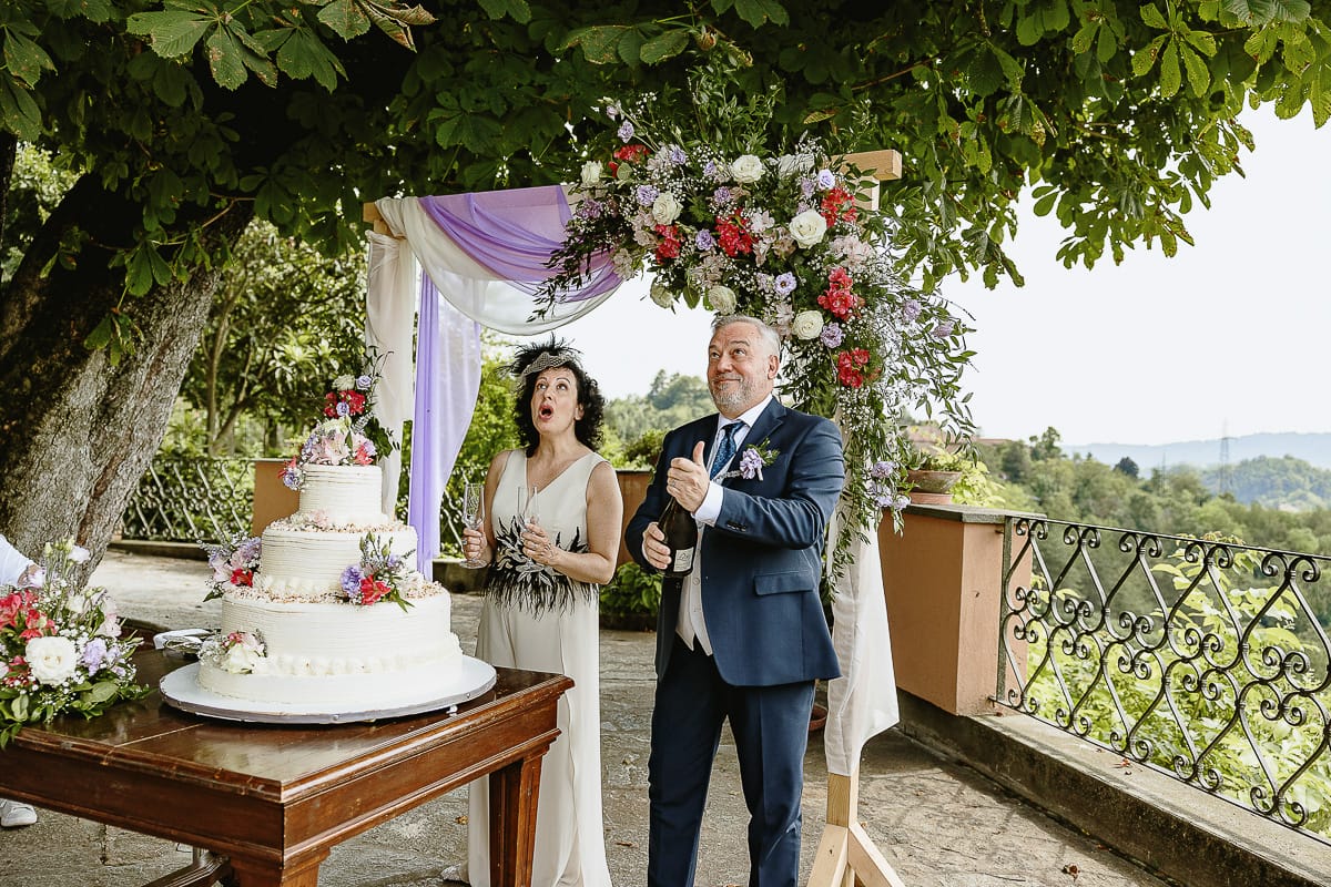 Fotografo matrimonio in Monferrato. Matrimonio di Serena e Fabrizio al Vecchio Castagno di Cocconato d'Asti. Taglio della torta. Sposo stappa la botiglia di spumante.