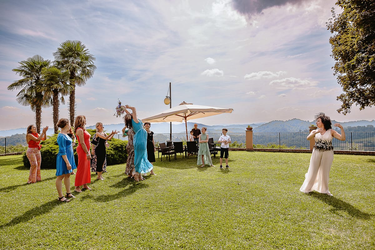 Fotografo matrimonio in Monferrato. Matrimonio di Serena e Fabrizio al Vecchio Castagno di Cocconato d'Asti. Lancio del bouquet. Secondo lancio valido. la ragazza lcon abito turchese lo prende al volo con un'acrobazia.