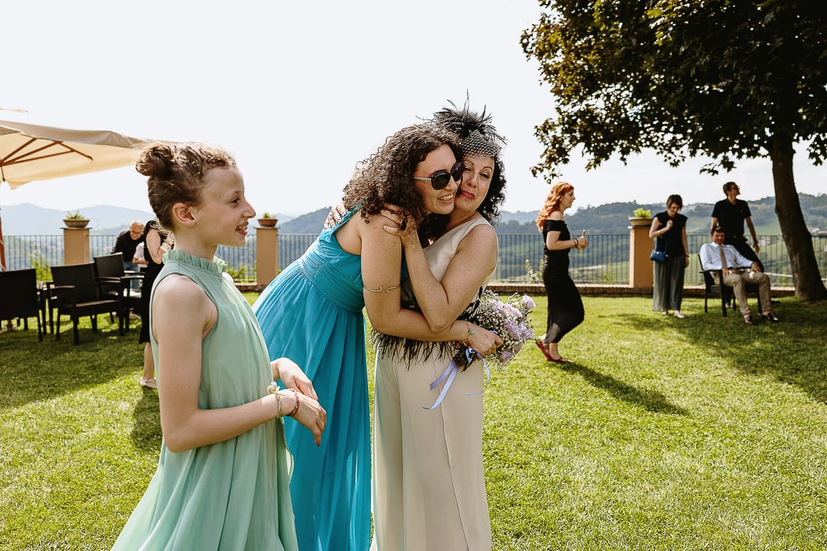 Fotografo matrimonio in Monferrato. Matrimonio di Serena e Fabrizio al Vecchio Castagno di Cocconato d'Asti. Lancio del bouquet. Abbraccio della sposa alla ragazza che ha preso il bouquet.