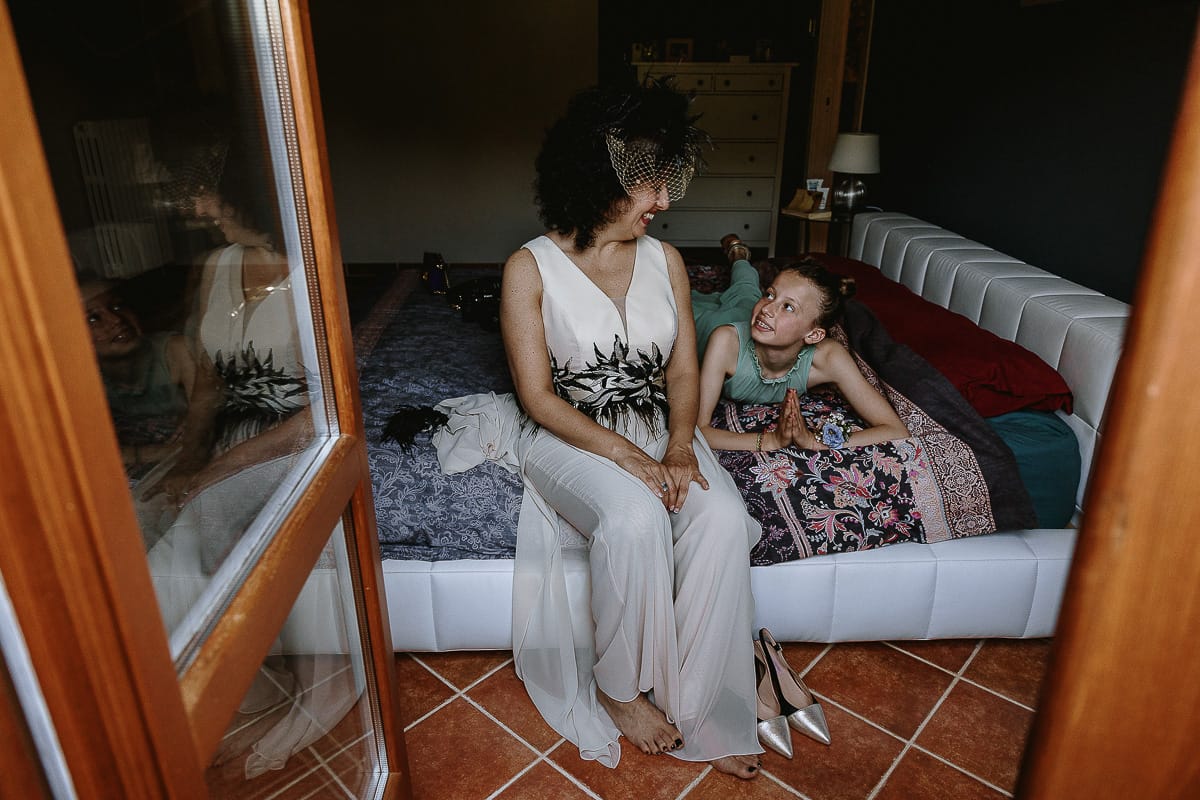Fotografo matrimonio in Monferrato. Matrimonio di Serena e Fabrizio. Preparazione a Baldissero Torinese. Sposa seduta sul letto guarda la nipotina.