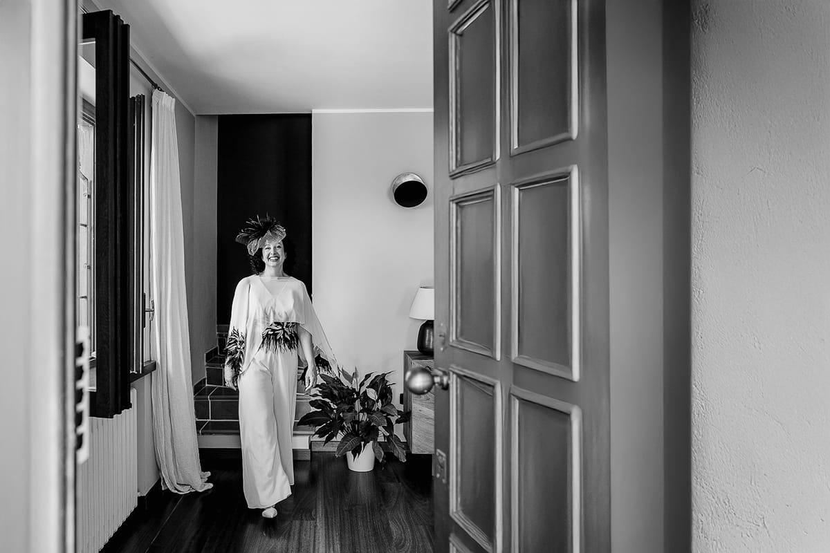 Fotografo matrimonio in Monferrato. Matrimonio di Serena e Fabrizio. Preparazione a Baldissero Torinese. Ritratto della sposa sorridente, ripreso dalla porta d'ingresso.