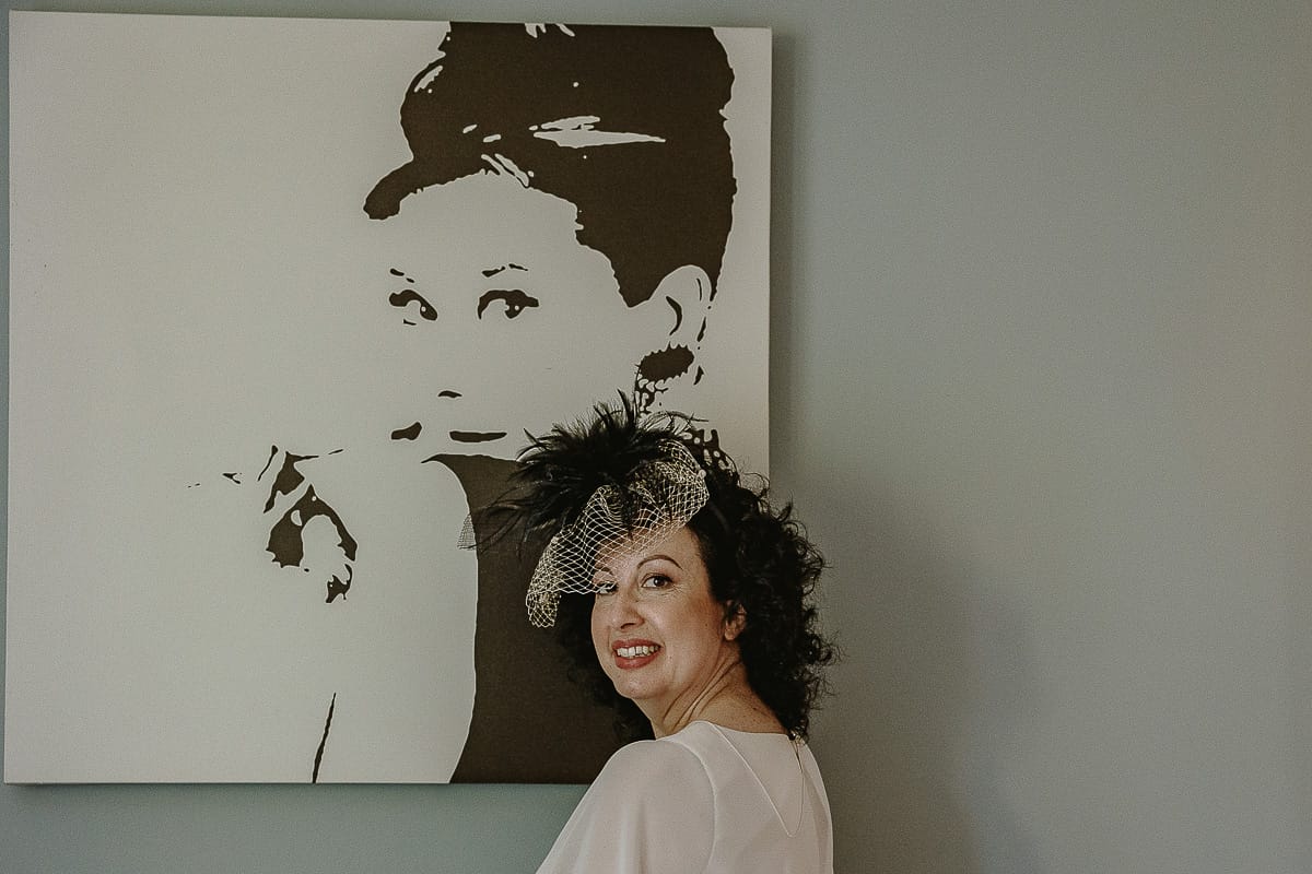 Fotografo matrimonio in Monferrato. Matrimonio di Serena e Fabrizio. Preparazione a Baldissero Torinese. Sposa davanti ad una stampa di Audrey Hepburn in "Colazione da Tiffany".