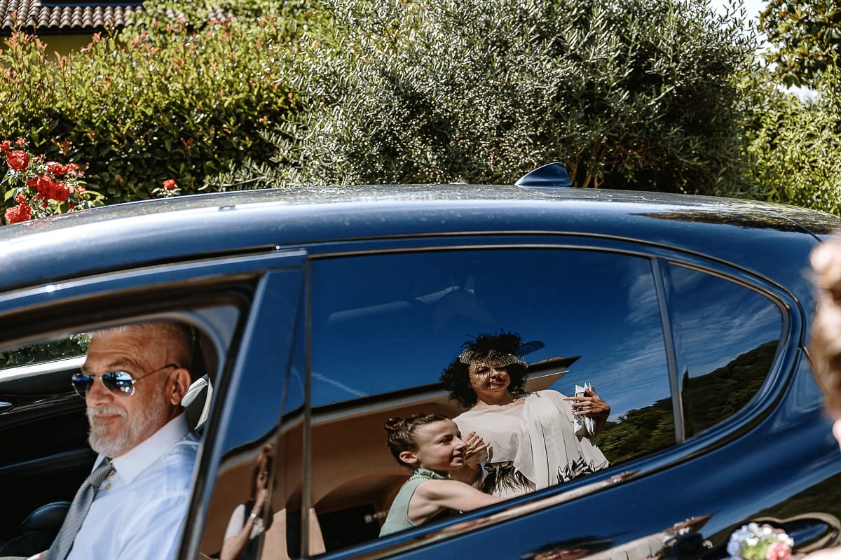 Fotografo matrimonio in Monferrato. Matrimonio di Serena e Fabrizio. Preparazione a Baldissero Torinese. Sposa riflessa nell'auto con la nipotina.