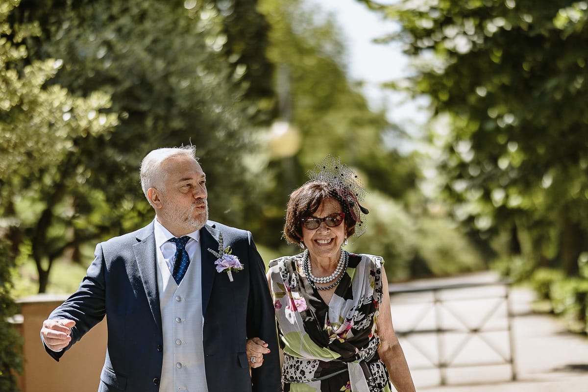 Fotografo matrimonio in Monferrato. Matrimonio di Serena e Fabrizio al Vecchio Castagno di Cocconato d'Asti.Sposo si dirige verso la zona della cerimonia al braccio della suocera.