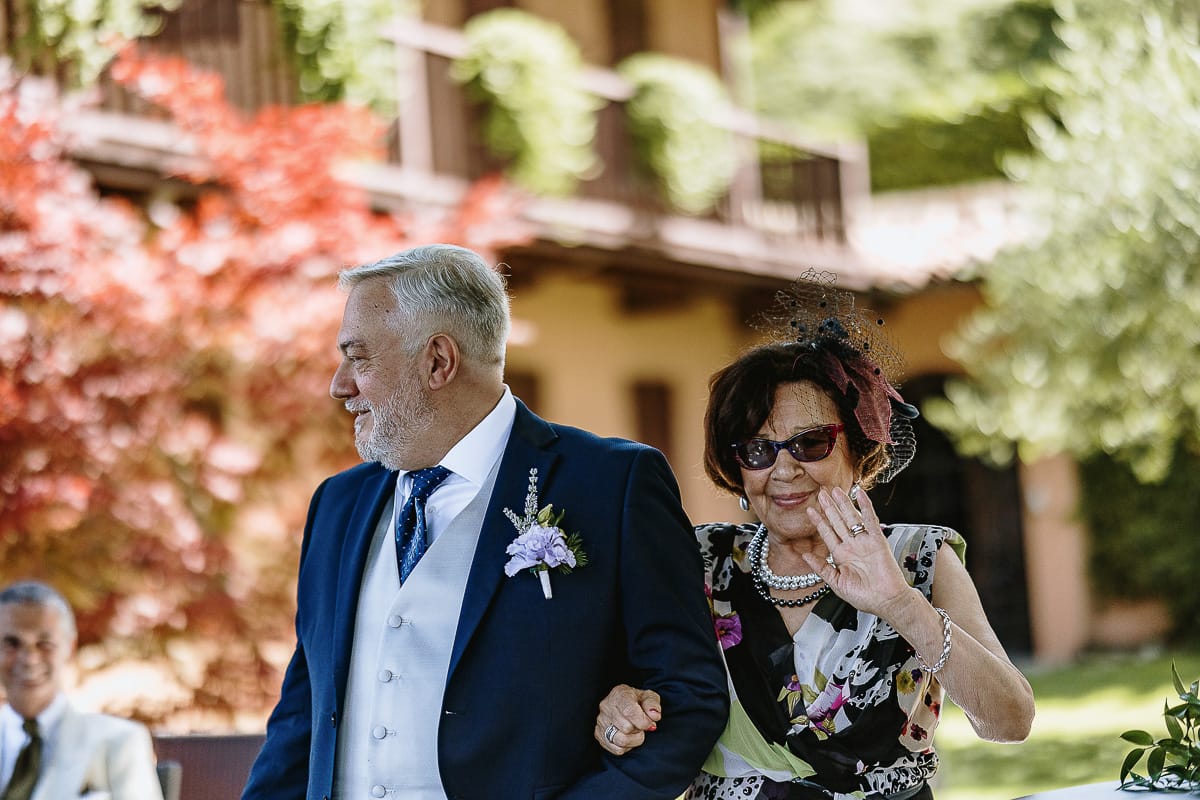 Fotografo matrimonio in Monferrato. Matrimonio di Serena e Fabrizio al Vecchio Castagno di Cocconato d'Asti.Sposo si dirige verso la zona della cerimonia al braccio della suocera.