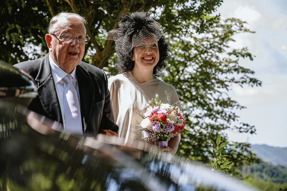 Fotografo matrimonio in Monferrato. Matrimonio di Serena e Fabrizio al Vecchio Castagno di Cocconato d'Asti. Sposa si dirige verso il luogo della cerimoni al braccio del padre.