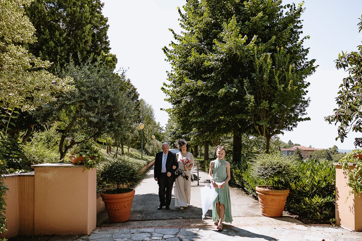 Fotografo matrimonio in Monferrato. Matrimonio di Serena e Fabrizio al Vecchio Castagno di Cocconato d'Asti. Sposa si dirige verso il luogo della cerimoni al braccio del padre. davanti c'è la nipotina.
