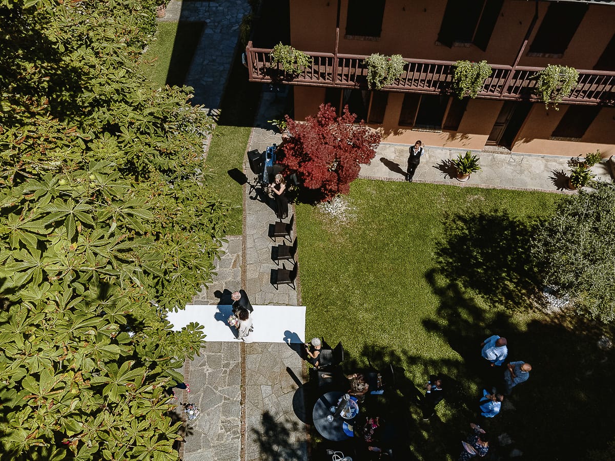 Fotografo matrimonio in Monferrato. Matrimonio di Serena e Fabrizio al Vecchio Castagno di Cocconato d'Asti. Sposa si dirige verso il luogo della cerimonia al braccio del padre. Foto aerea dal drone.